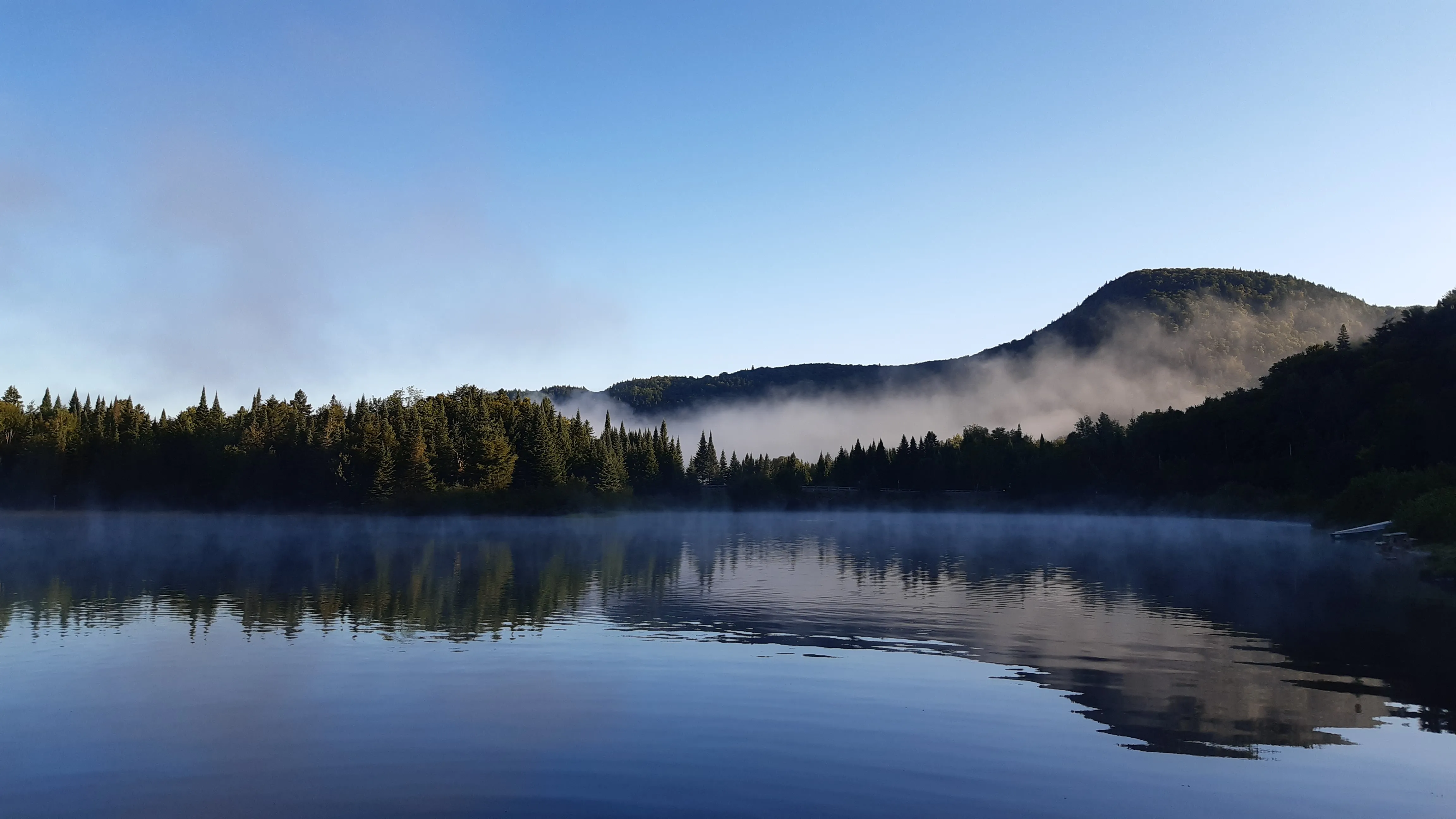 Mountain behind lake covered with fog
