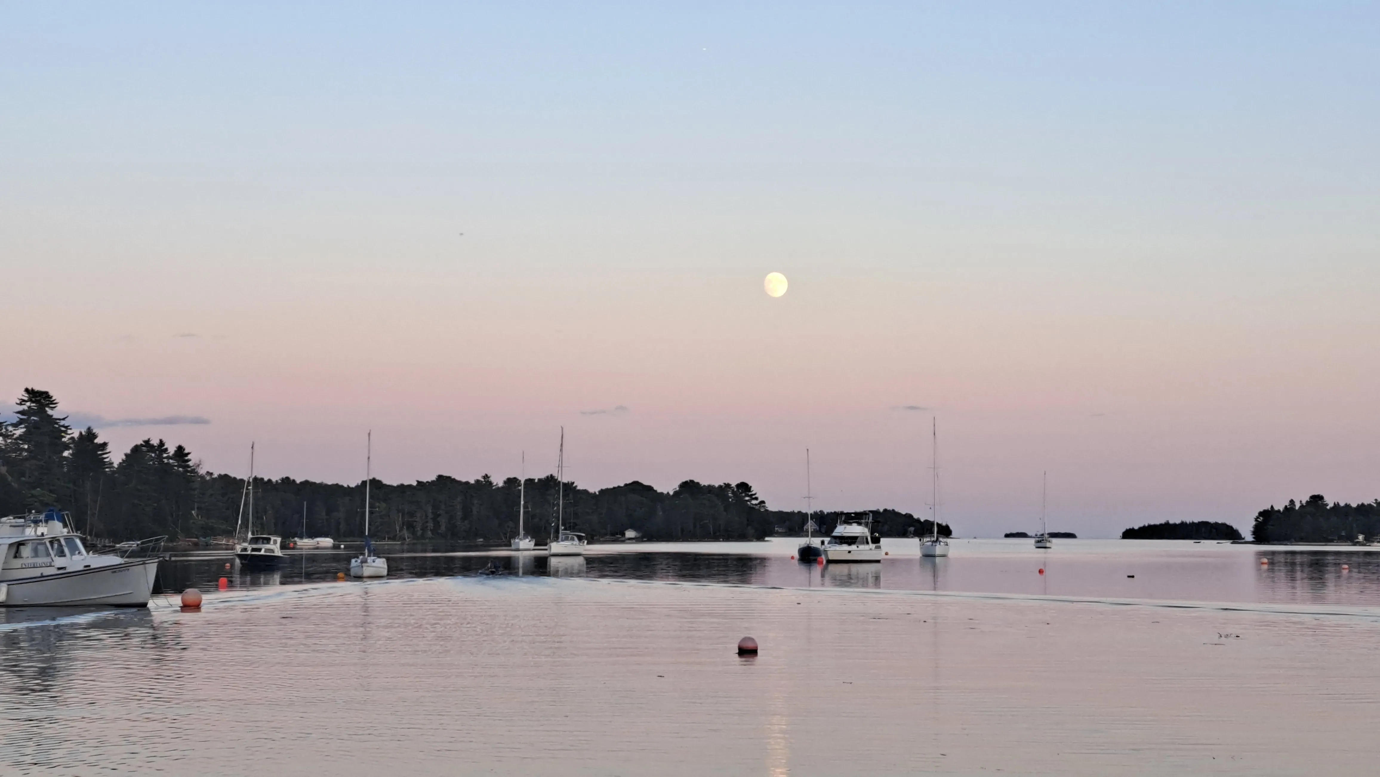 Pink and blue sunset above lake with boats