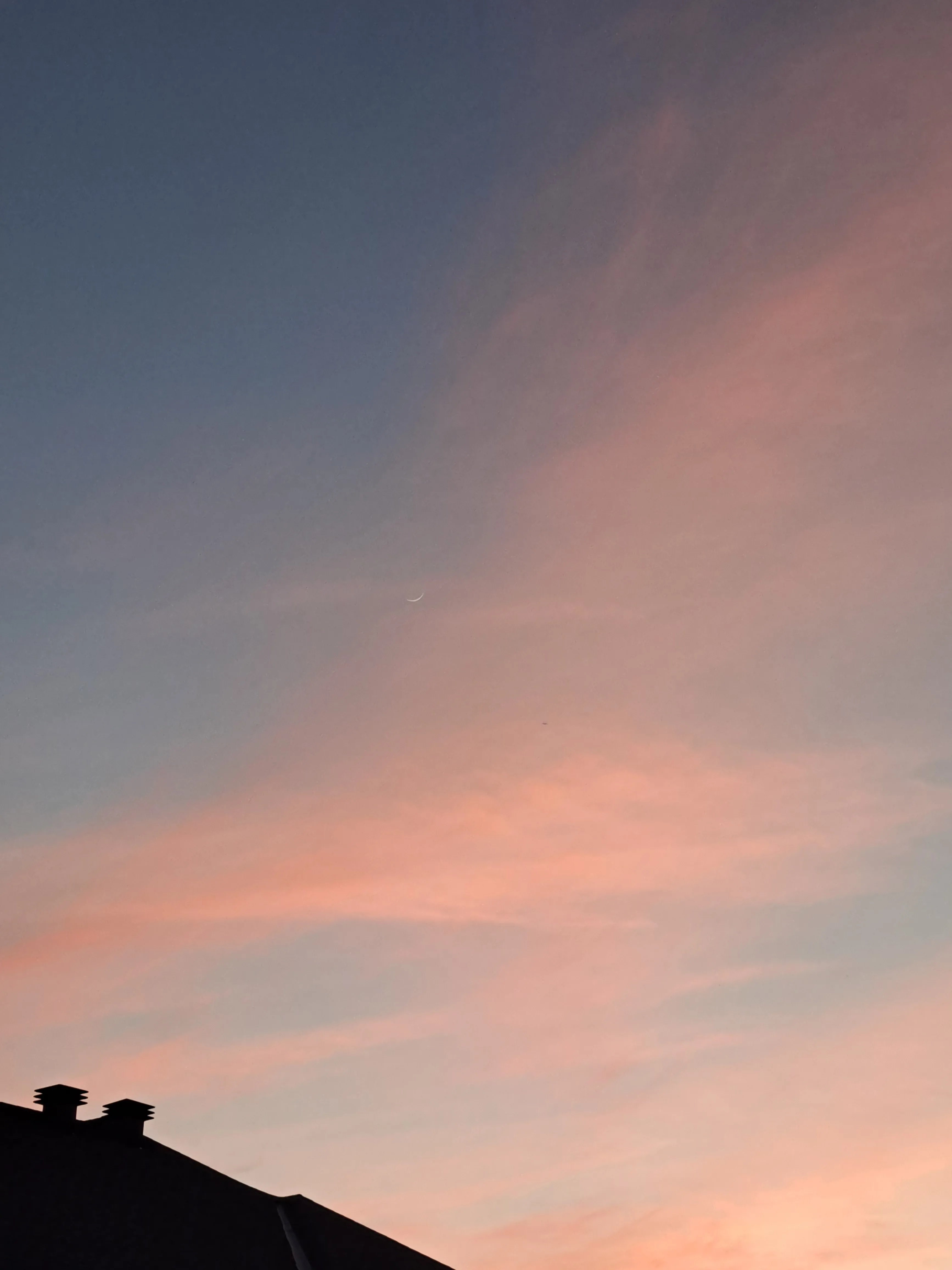 Pink and blue sunset above roof of house