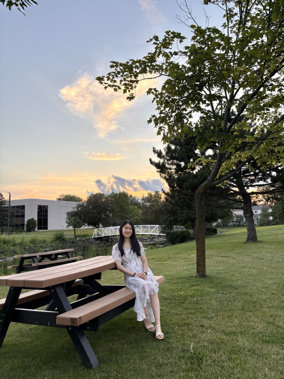 Angela sitting on a picnic bench wearing a long purple flowery dress and sandals