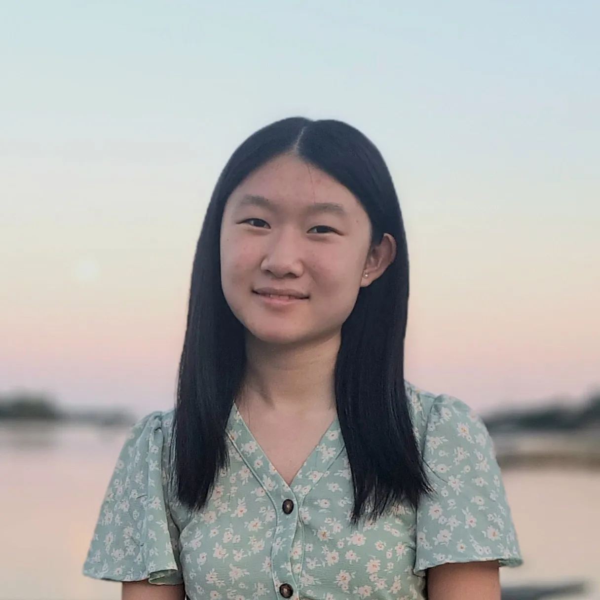 Angela in front of a pink and blue sunset