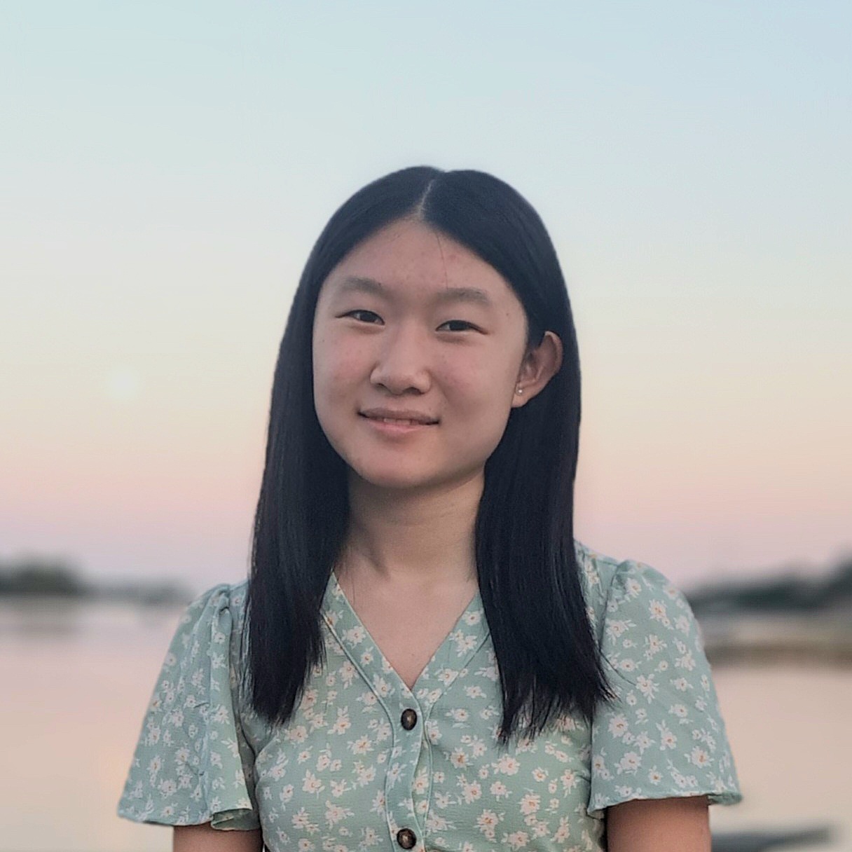Angela in front of a pink and blue sunset
